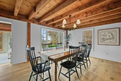 Bright rustic dining room with exposed beams and peaceful outdoor views