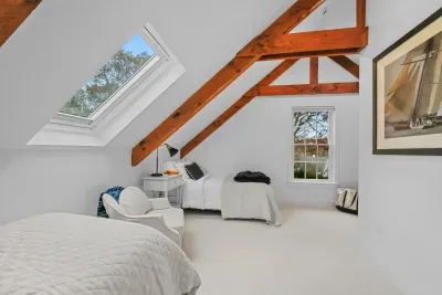 Bright loft bedroom with exposed beams, skylight, and two cozy beds