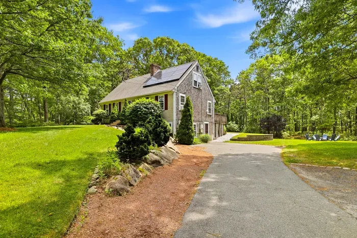Private wooded retreat with spacious lawn, long driveway, and sunny outdoor seating