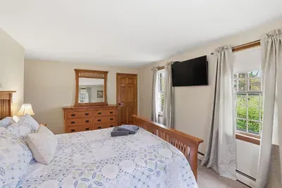 Bright, spacious bedroom with natural light, TV, and classic wood furnishings