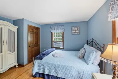 Charming blue bedroom with cozy linens, vintage touches, and Window AC comfort