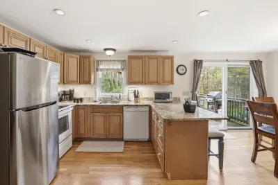 Bright open kitchen with granite counters, breakfast bar, and deck access