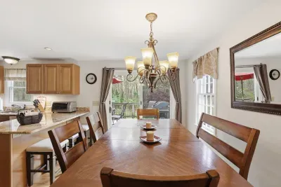 Bright dining room with deck access, wooded views, and open kitchen seating