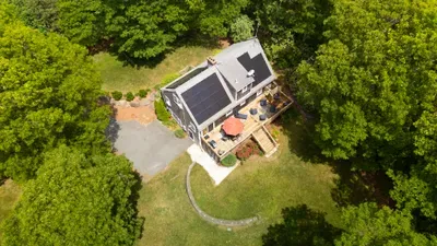 Private wooded retreat with spacious deck, lawn, and eco-friendly solar panels