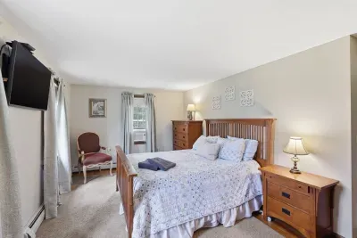 Cozy queen bedroom with TV, AC, and warm wood furnishings
