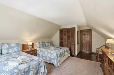 Charming attic bedroom with two beds, warm wood accents, and cozy lighting