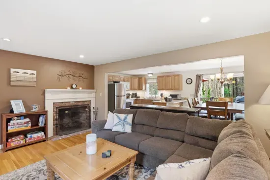 Cozy open living space with fireplace, large sectional, and bright kitchen