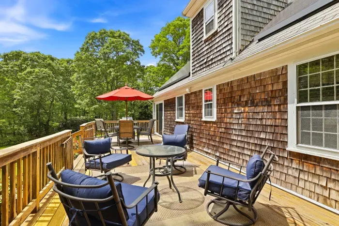 Sunny private deck with lounge seating, dining area, and wooded views