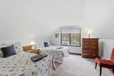 Cozy twin bedroom with natural light, leafy views, and attic charm
