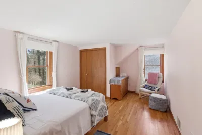 Sunlit bedroom with hardwood floors, reading nook & forest views