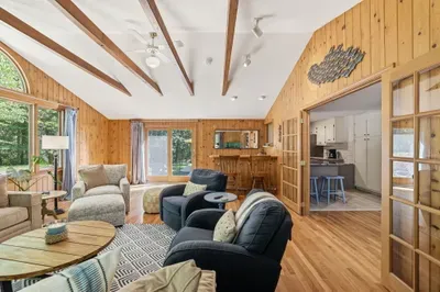 Vaulted wood-paneled living room with forest views and cozy seating