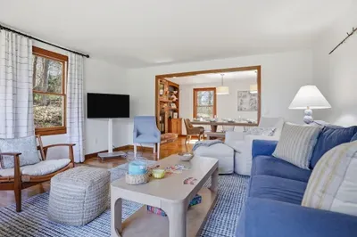 Sunny lounge with TV, games, and open flow to dining room; comfy seating throughout.