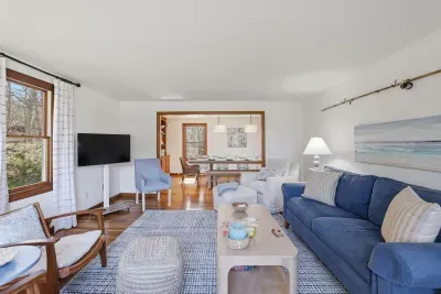 Sunny coastal living room with comfy seating, TV, and open dining flow