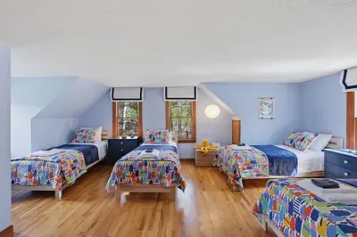 Sunny kids’ room with 5 twin beds, hardwood floors and playful decor