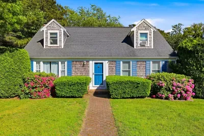 Charming cottage exterior with lush lawn, blooming gardens, and blue door