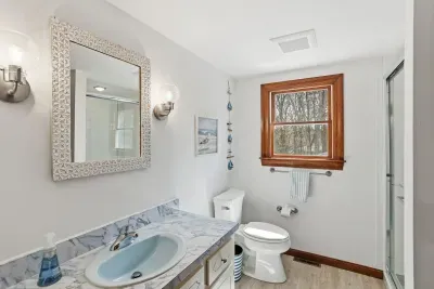 Bright bath with marble vanity, glass shower, and wood-trim window