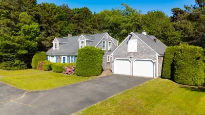Charming Cape-style home with 2-car garage, lush lawn, and private setting