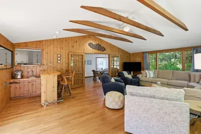 Spacious wood-beamed living room with large windows and cozy seating
