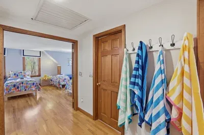 Sunny twin room with hardwood floors, towel hooks, and playful decor