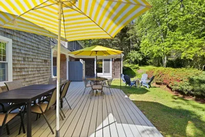 Sunny deck dining with shaded seating and backyard fire pit area