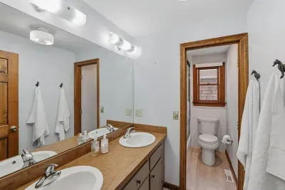 Bright bath with double vanity, large mirror & private toilet alcove