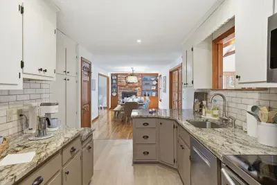 Updated kitchen with granite, coffee bar + open dining to brick hearth.