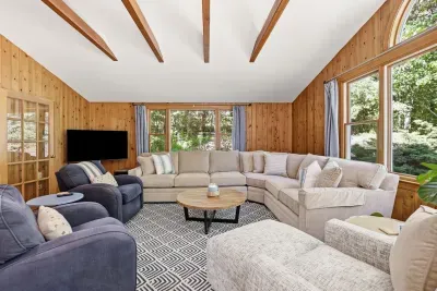 Bright wood-paneled living room with oversized sectional and serene views