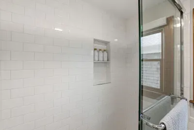Bright subway-tile shower with glass door, built-in niche & natural light