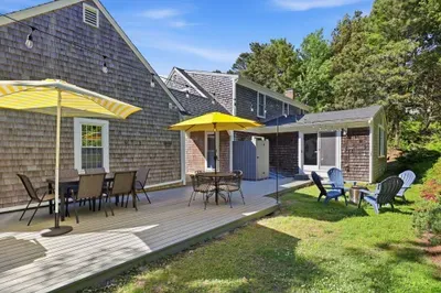 Sunny backyard deck with shaded dining and relaxing Adirondack seating