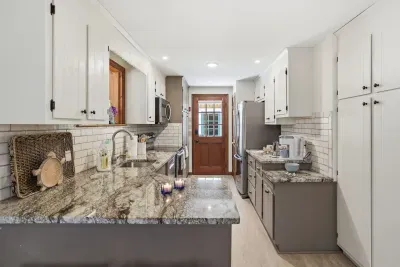 Bright galley kitchen with granite counters, subway tile and stainless steel