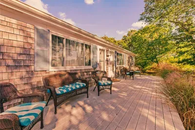 Sunny wraparound deck with cushioned seating and woodland views