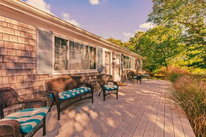 Sunny wraparound deck with cushioned seating and woodland views