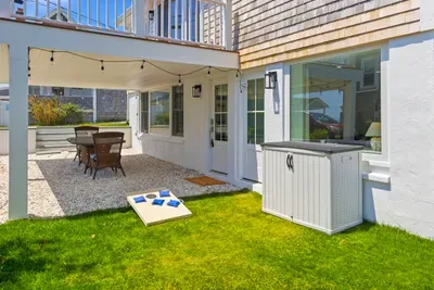 Private covered patio with outdoor dining, lawn games, and cozy string lights