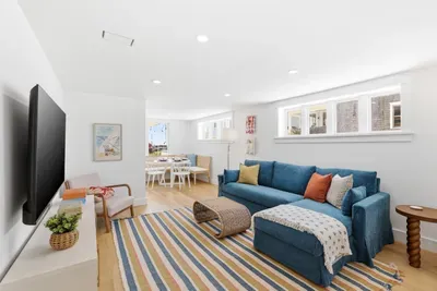 Bright open living room with blue sectional, large TV, and cozy dining nook