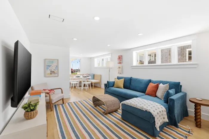 Bright open living room with blue sectional, large TV, and cozy dining nook