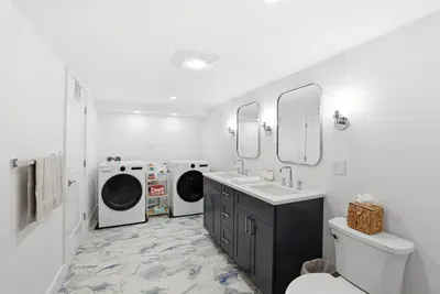 Bright modern bath with double vanity and full-size washer/dryer