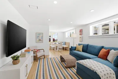 Bright coastal living room with sectional, TV, and cozy dining nook