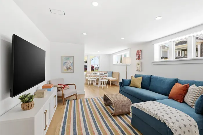 Bright coastal living room with sectional, TV, and cozy dining nook