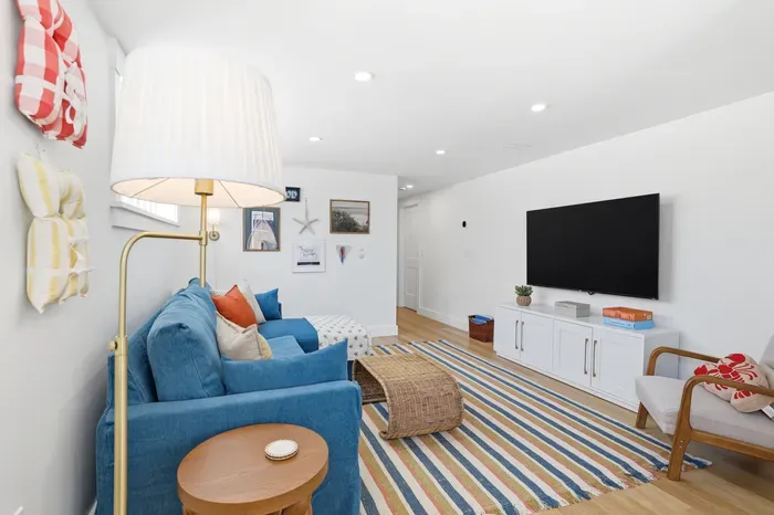 Bright coastal living room with big TV, comfy seating, and stylish decor