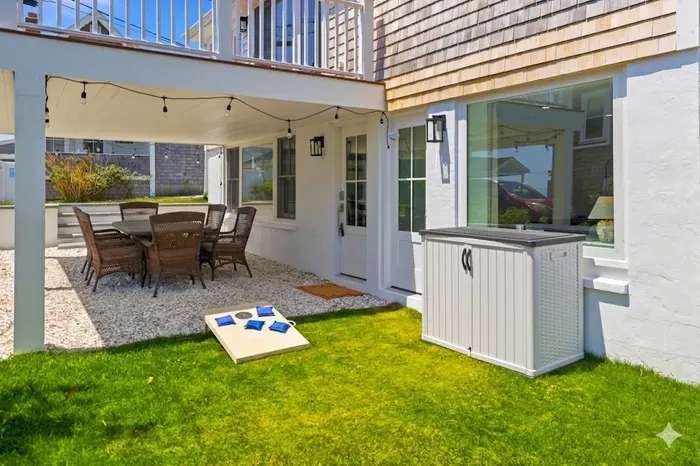 Covered patio with outdoor dining, lawn games, and inviting backyard space