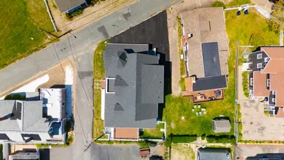 Aerial view of corner-lot home with spacious yard and ample parking