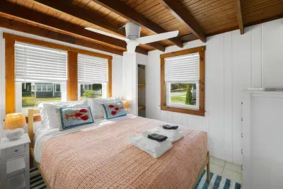Relax in this room featuring a queen-size bed, complete with charming decorative lobster cushions salmon colored linens for a touch of coastal flair.






