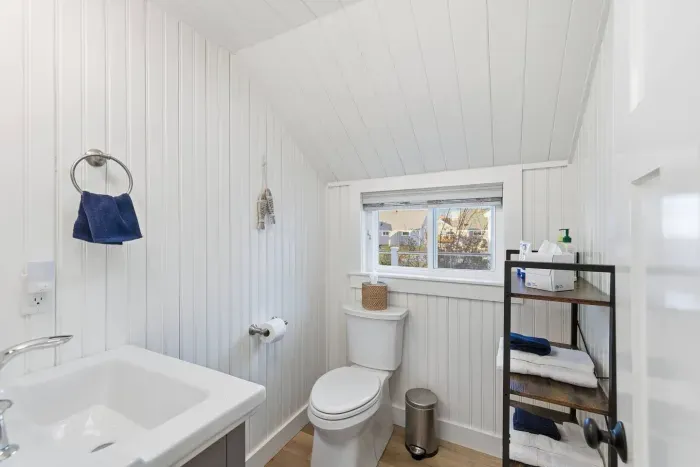 Convenient Half Bathroom: Thoughtfully designed with a bright window and extra shelving for guest convenience.