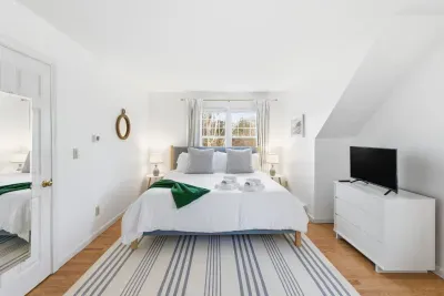 The room features a king bed, TV, natural light and clean coastal decor, offering a peaceful place after a day of Cape Cod adventures.