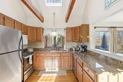 Our bright kitchen features high vaulted ceilings with rustic wood beams and a skylight that fills the space with natural warmth