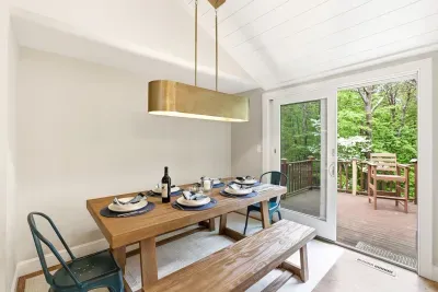 Bright dining nook with modern lighting and deck access surrounded by trees