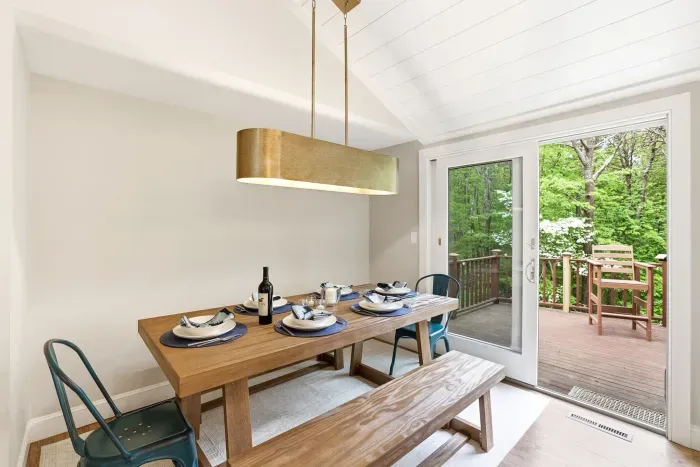 Bright dining nook with modern lighting and deck access surrounded by trees