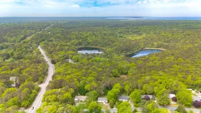 Scenic aerial view with wooded privacy, ponds, and nearby water vistas