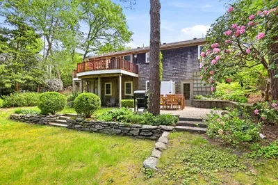 Private garden patio with deck, outdoor dining, and lush landscaped yard