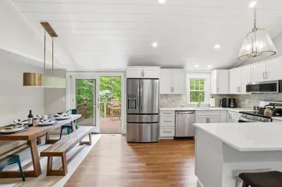 Bright modern kitchen with island, dining area, and deck access